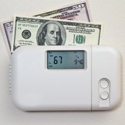 In door heating thermostat set at a room temperature and money